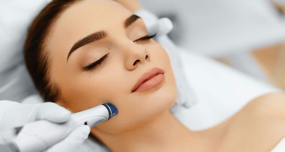 A facial device guided along the jawline during a treatment